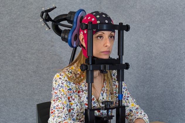 Participant wearing waveguard EEG cap on chinrest with a TMS coil placed on her head.