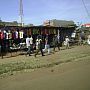 Kenyans passing market stall selling lots of vibrantly coloured t-shirts