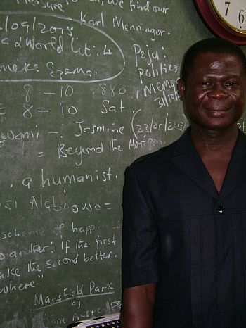 Picture of Dr Oloko standing by his writing-filled chalkboard