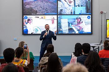 Jorge Ortiz Moreno presenting to an audience. Behind him is a PowerPoint with images relating to rainwater harvesting.