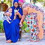 two women in Tanzania, one woman is holding a baby and looking at her phone while the other looks at the phone over her shoulder
