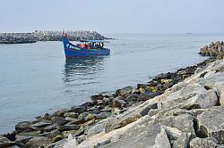 A larger fishing boat approaches the fishing harbour near Anchuthengu village, between stone structure that sometime cause accidents.