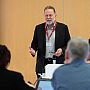 Zoomed in photo of Prof Peter Taylor presenting on "Impactful, equitable partnerships" with a few blurred attendees seen in the foreground