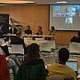 Group of people sitting on chairs and listening to our "Equitable Partnerships" panel feat. SSRP researchers and their project partners from abroad. The Chair Prof Robin Banerjee can be seen facilitating the session, while three of the panelists are seated to the right of Robin and the remaining two online panelists are pictured via a big screen