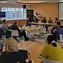 Group of people sitting on chairs and listening to our "Equitable Partnerships" panel feat. SSRP researchers and their project partners from abroad. The Chair Prof Robin Banerjee can be seen facilitating the session, while three of the panelists are seated to the right of Robin and the remaining two online panelists are pictured via a big screen