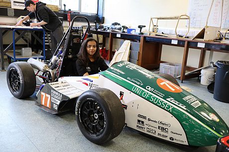 Abigail Berhane sits in the formula car 2018, in the middle of a workshop.