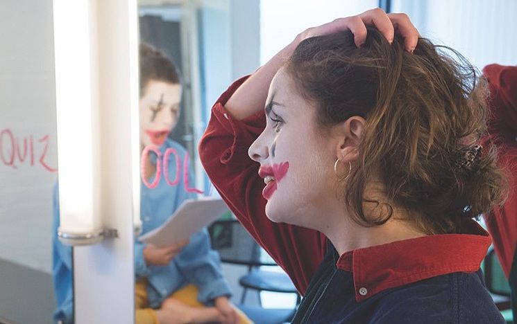 Girl getting ready for a drama performance applying make-up in a mirror