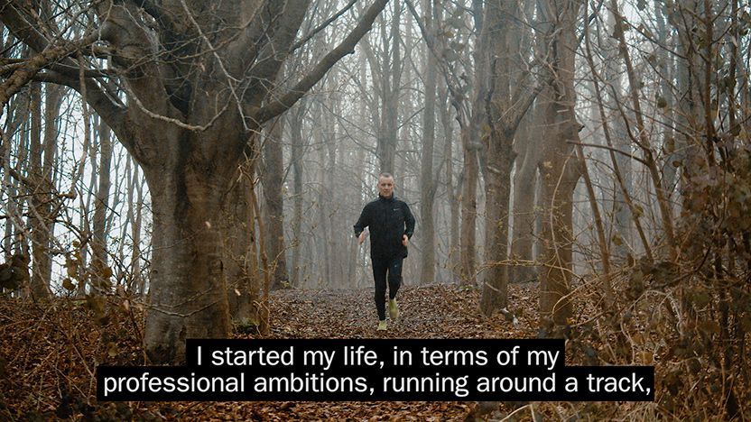 A video still showing a man jogging near campus with two lines of subtitle