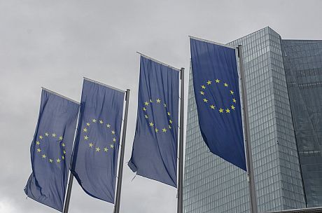 A row of EU flags flying in front of a large office building