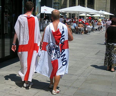 A photo of some England football fans draped in the English football team's flag