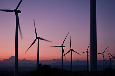 A photo of some wind turbines at dusk against a purple sky