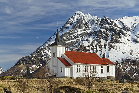 A photo of a wooden church, set against a background of an imposing snow-capped mountain