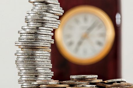 A photo of a stack of coins, with a clock in the background
