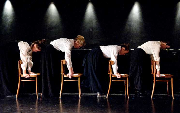 4 people bending forward over 4 chairs