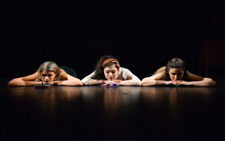 Three women lying face down on the floor looking towards the camera