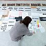 A person laying out printed pieces of paper on the floor to dry
