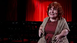 Woman sitting in front of a stage with a red curtain