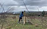 Adrian Kaluka performing maintenance on a wooden monitoring station in a field on the Wiston Estate