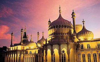The top half and roof of the pavilion lit up against a purple, pink, orange sunset sky.