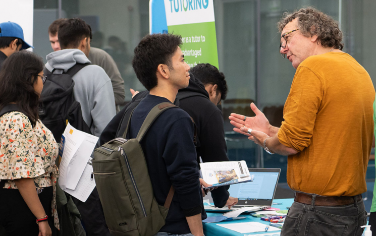 A student talks to an employer at a stand in a careers fair.