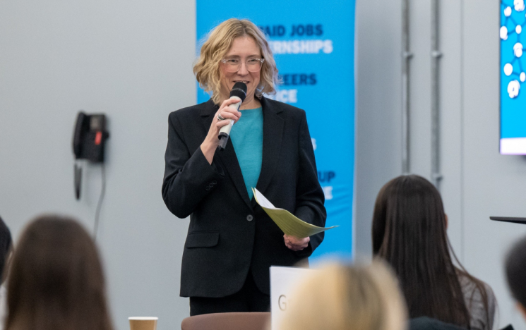 Emily Huns (head of Careers team) stands with a microphone and presents to a room of students.
