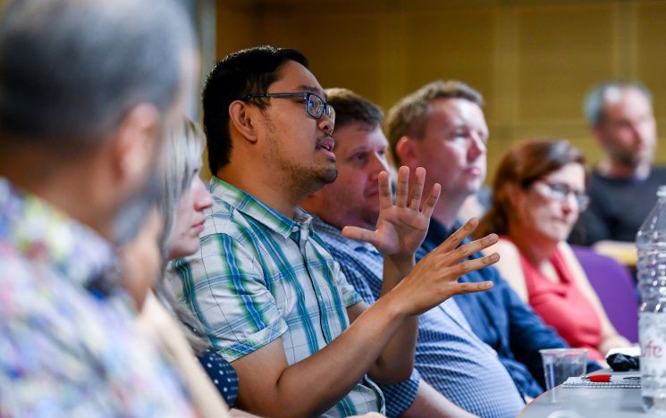 Member of staff sitting in lecture theatre in discussion