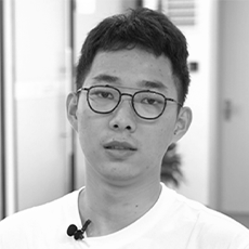 Student in white t-shirt and glasses looking at the camera.