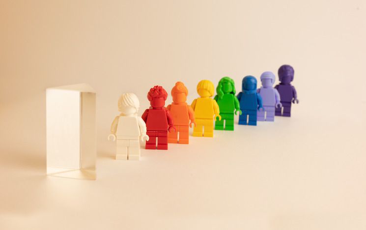 Prism with white lego man and rainbow coloured lego men/woman standing behind