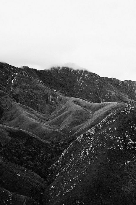 Black and white mountains with some clouds near the peaks
