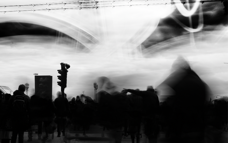 Black and white image of a crowd walking under a bridge