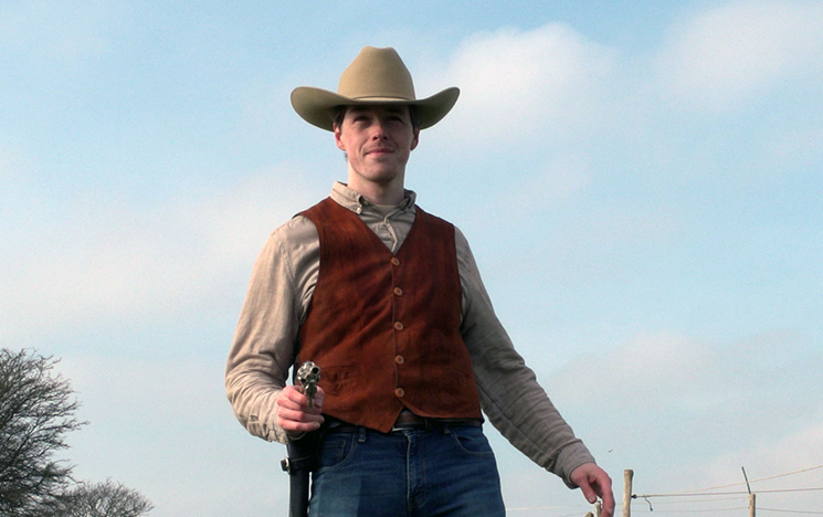 A man in a cowboy hat holding a gun
