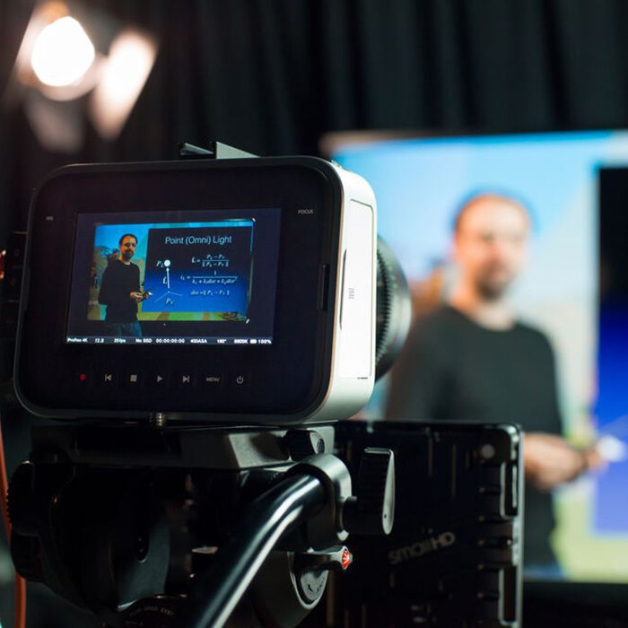 Camera filming a man giving a presentation, with the speaker visible on the camera screen