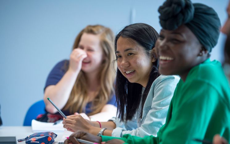 three students seen laughing in a seminar room