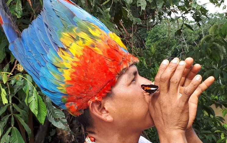 Man wearing feather wig blowing an instrument