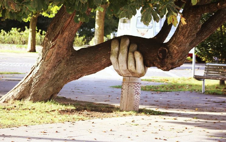 Carved hand holding up a falling tree