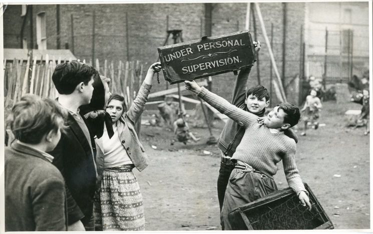 Old photo of children playing - holding up sign saying 'under personal supervision'