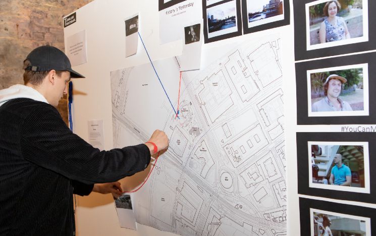 Person looking at a poster board covered in photos and blueprints of the Southbank