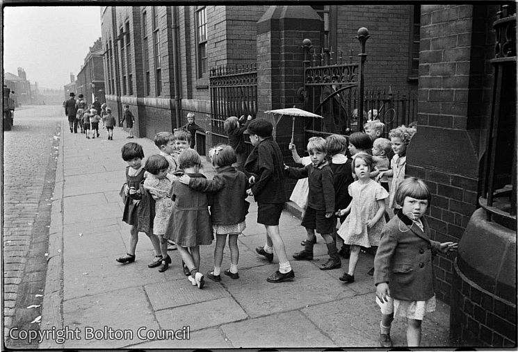 A black and white photo of schoolchildren outside their school in 1937
