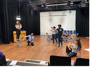 Actors stand on a stage working out positions