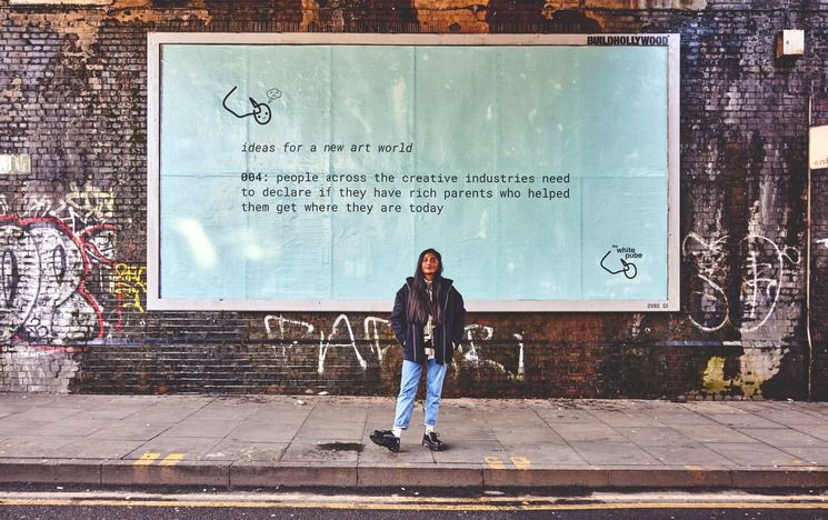 Zarina Mohammed standing in front of a billboard promoting The White Pube and new ideas for the art world