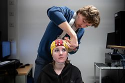 Researcher putting on an EEG cap (which records brain signals) on a participant