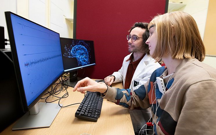 Two researchers study data on a computer 