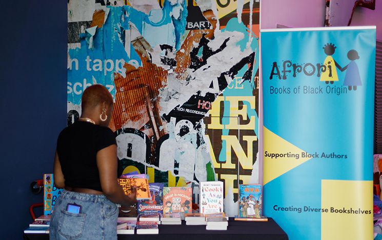 A woman holding some books and standing at Afrori book stall