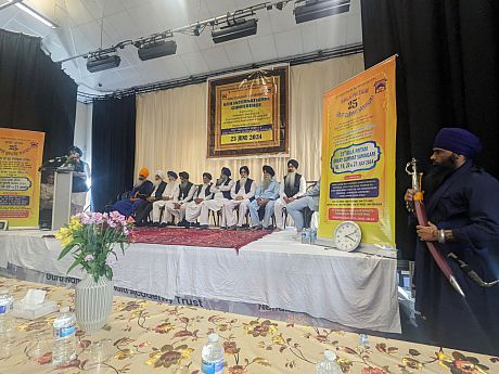 The delegates of the Nehkaame Sewa & Guru Hargobind Singh Trusts at the 6th International Conference, sat on a raised stage