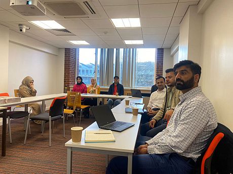 PhD students sat at tables at a workshop for Afghan students at the University of Sussex