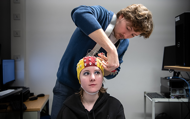 A man fitting an EEG cap onto a woman's head.