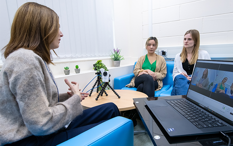 A woman interviewing two others as part of a study.