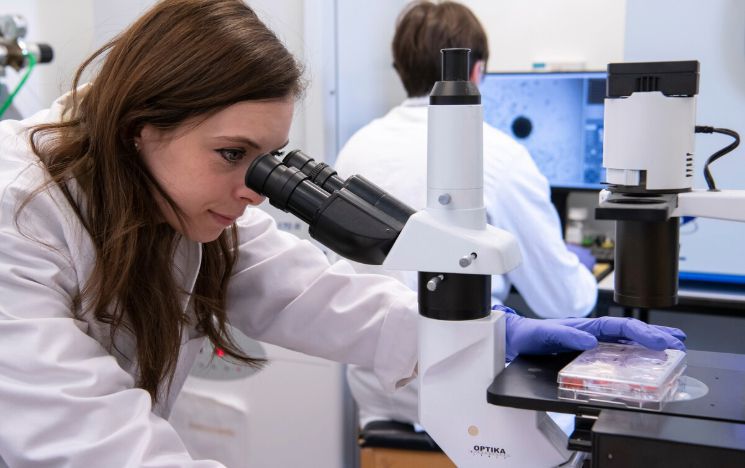A student inspects a microscope in a laboratory