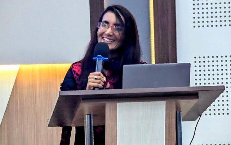 Raminder speaking into a microphone at a lecturn