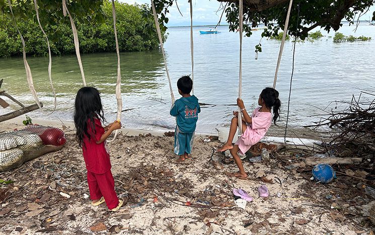 Children on rope swings on the edge of the beach